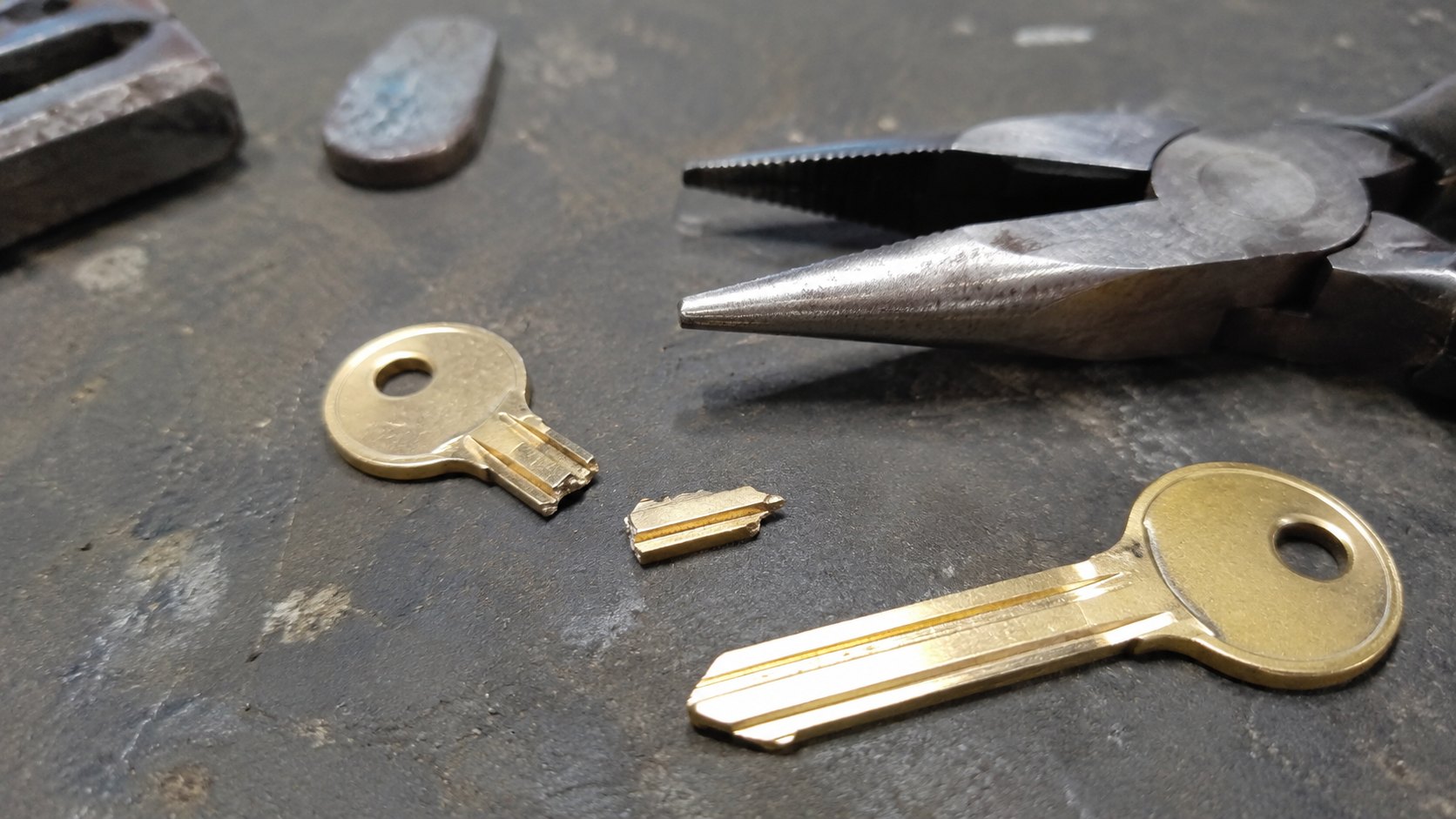 The snapped end of a key in a door lock with an extraction tool beside it