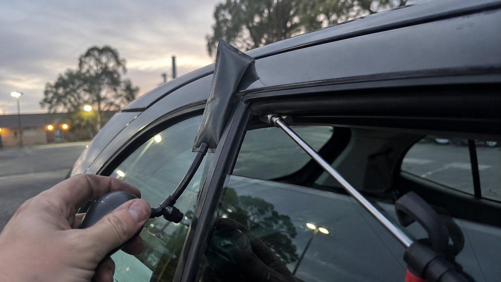An inflatable wedge and long reach tool at the top corner of a car door