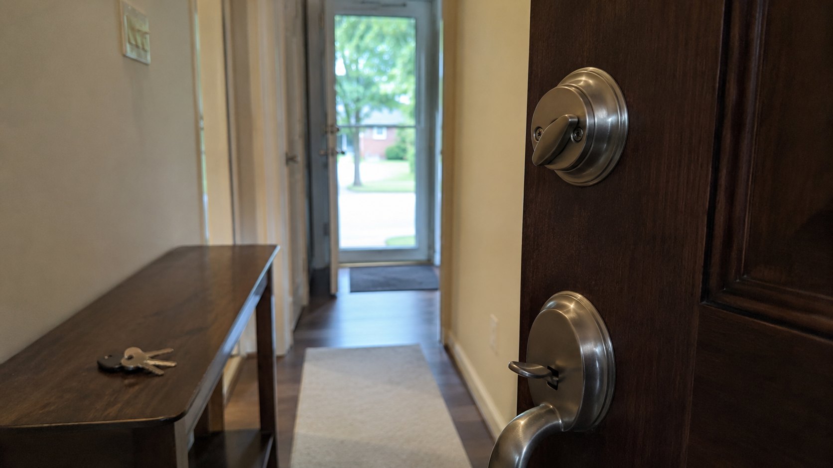 A hallway looking towards a front door with the deadbolt thrown and keys on the table