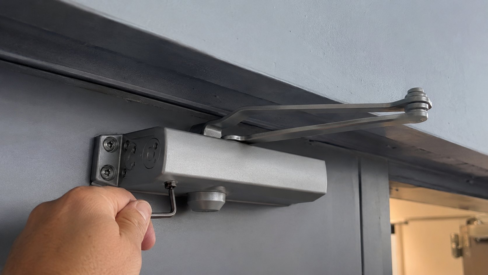 An overhead door closer with a hex key at its adjustment valves