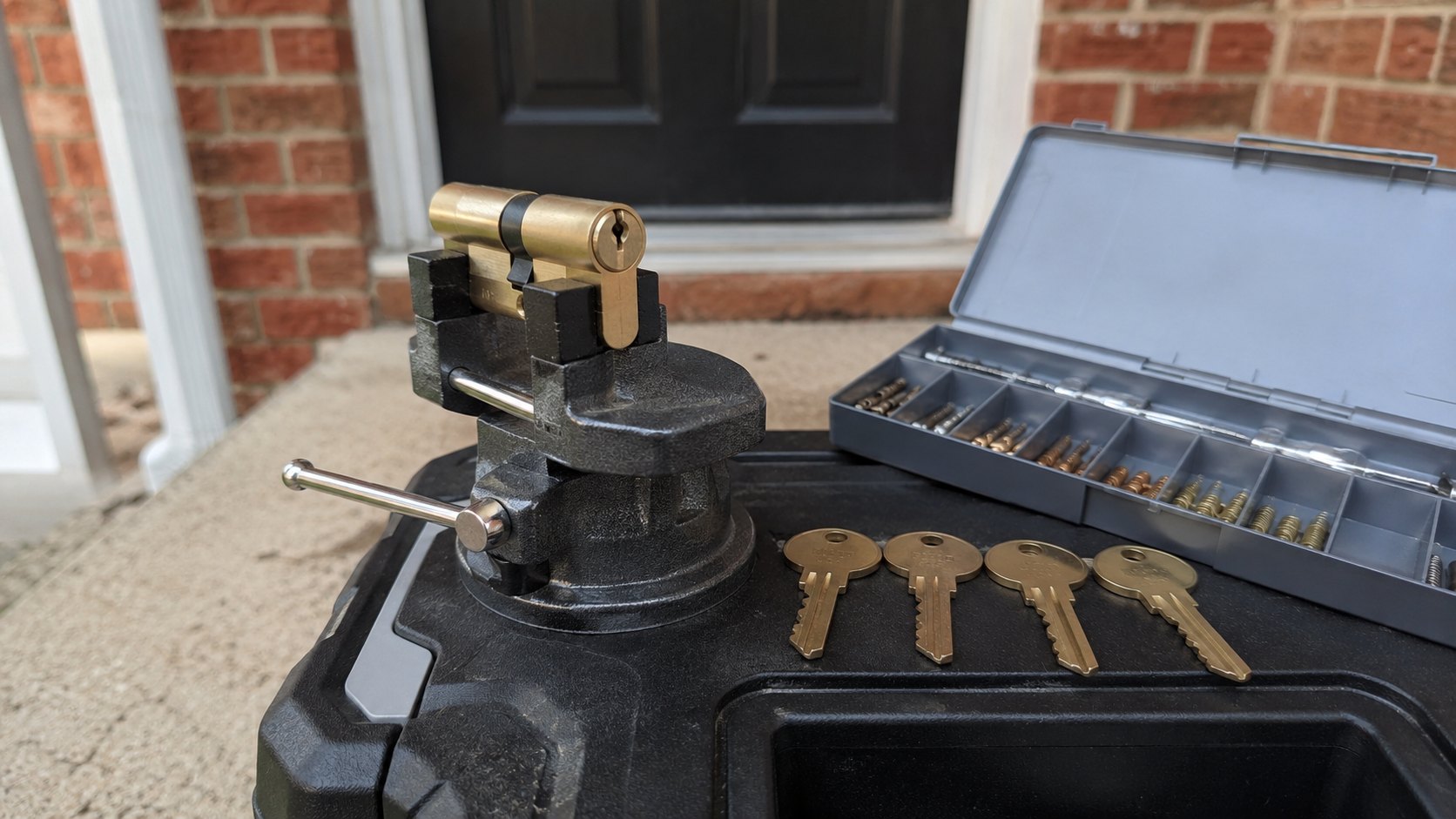 A front door cylinder out of the door at dusk with a fresh set of keys beside it