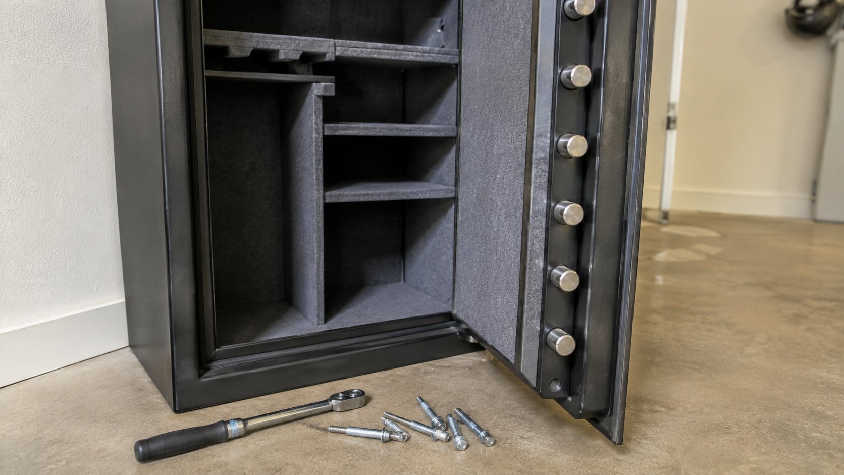 An open gun safe showing its bolt array, with anchor bolts and a torque wrench in front