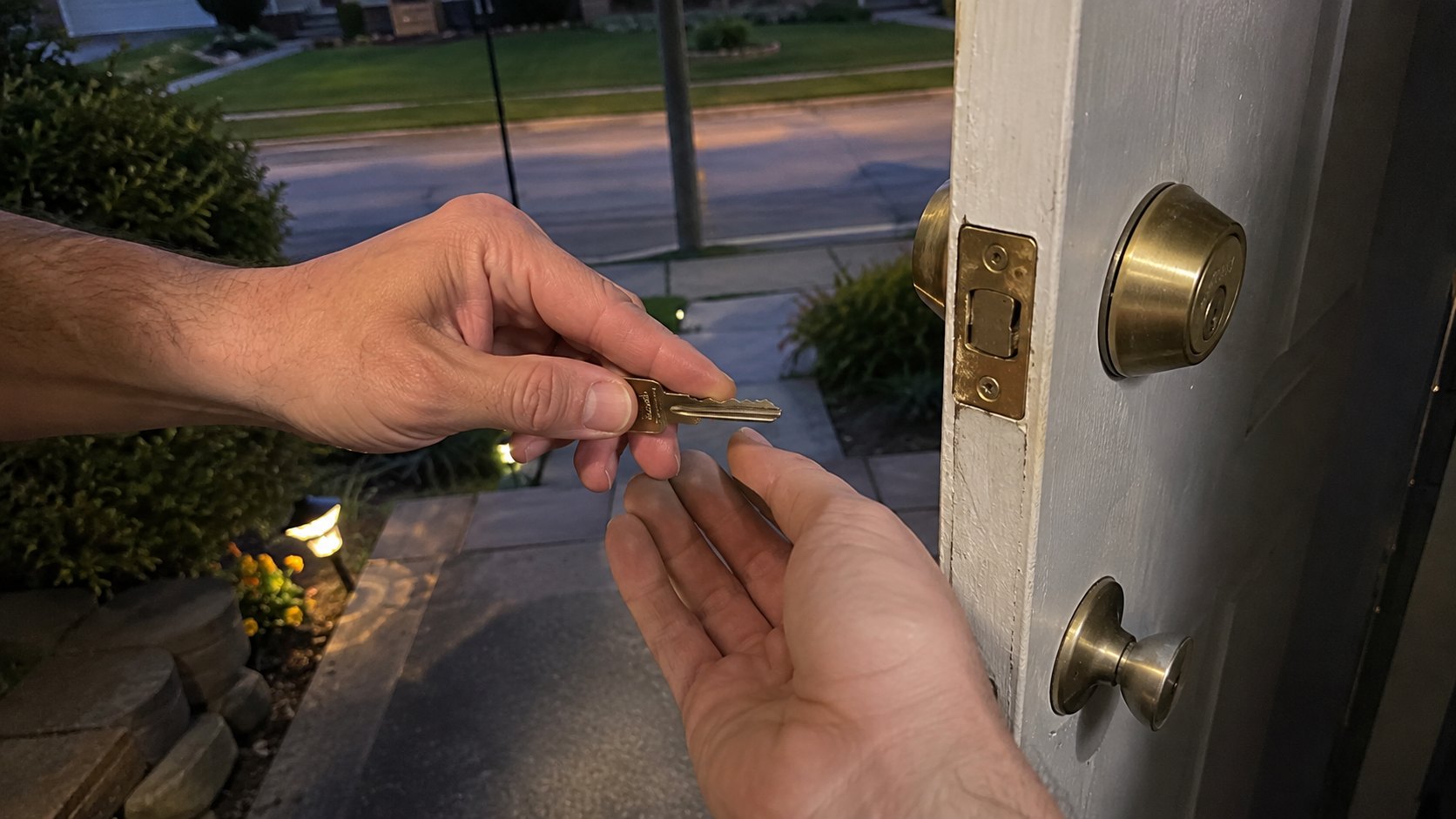 Lock picks and a tension wrench in the keyway of a house deadbolt at dusk
