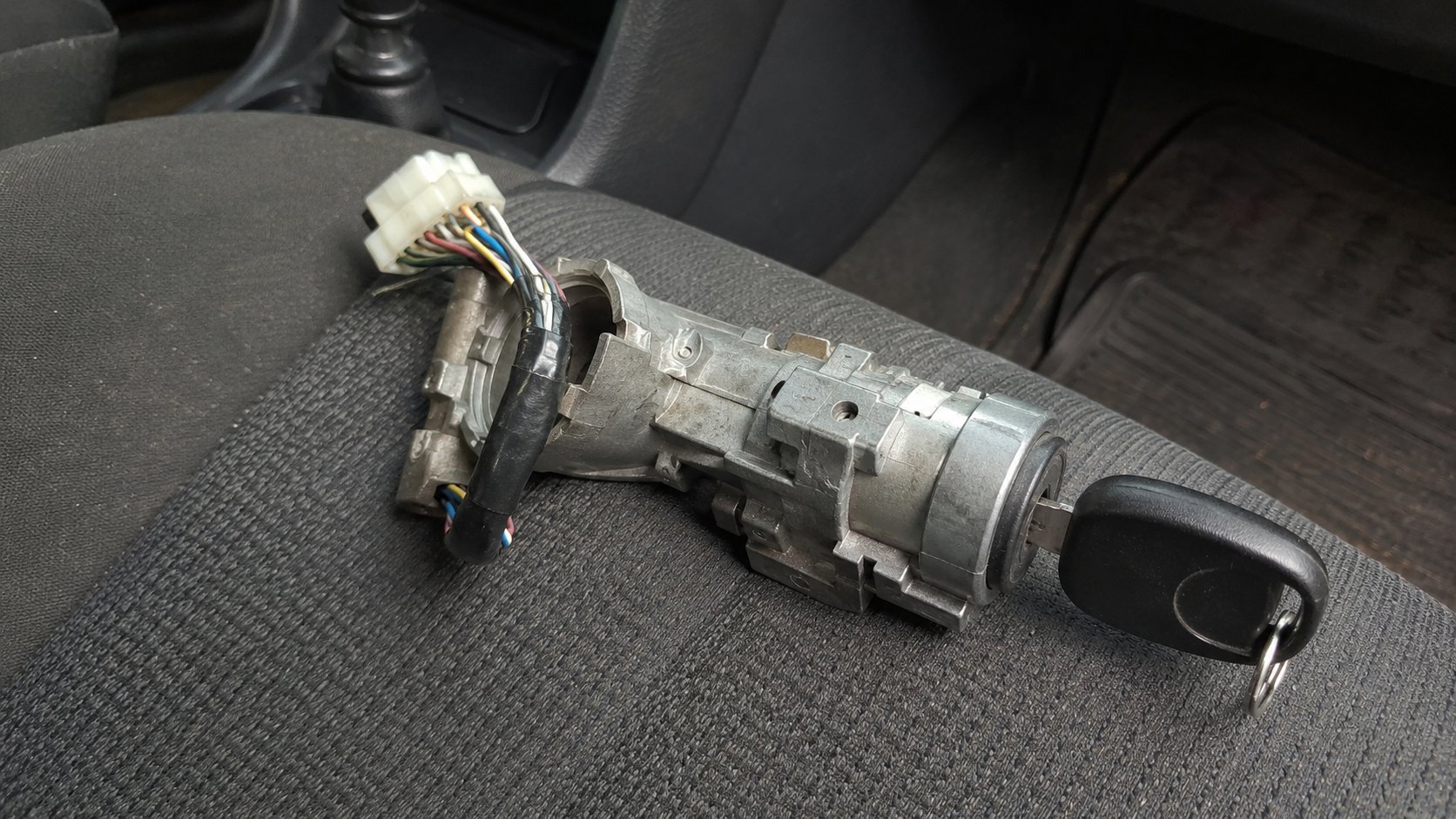 A car ignition barrel removed from the steering column, key still in it