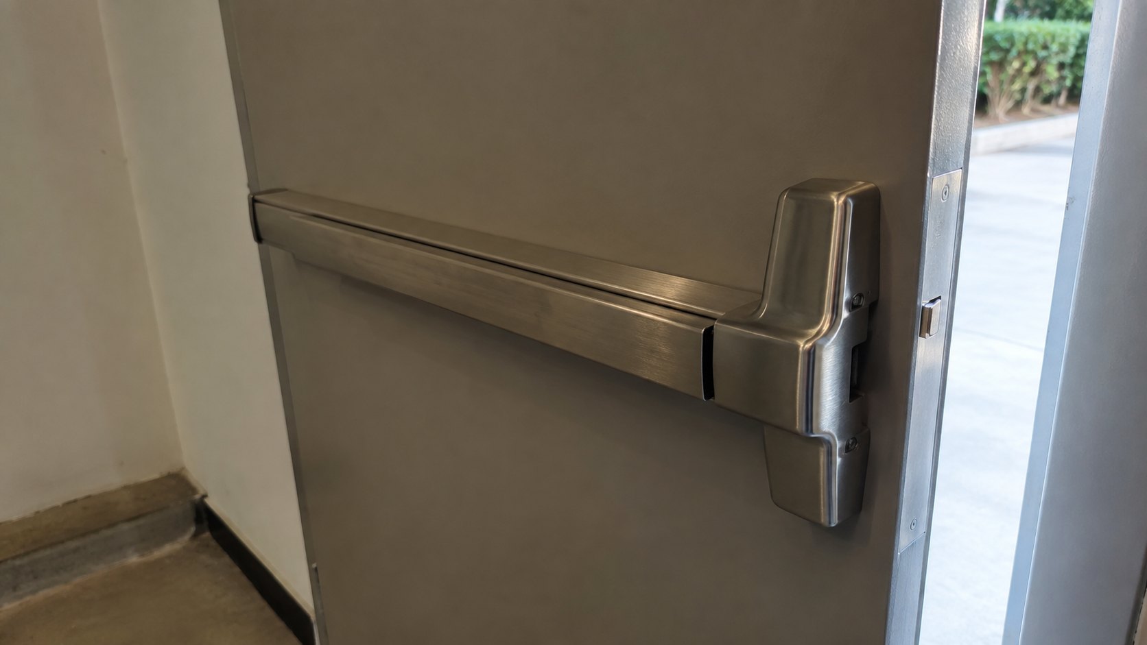 A stainless push bar on a commercial exit door seen from inside