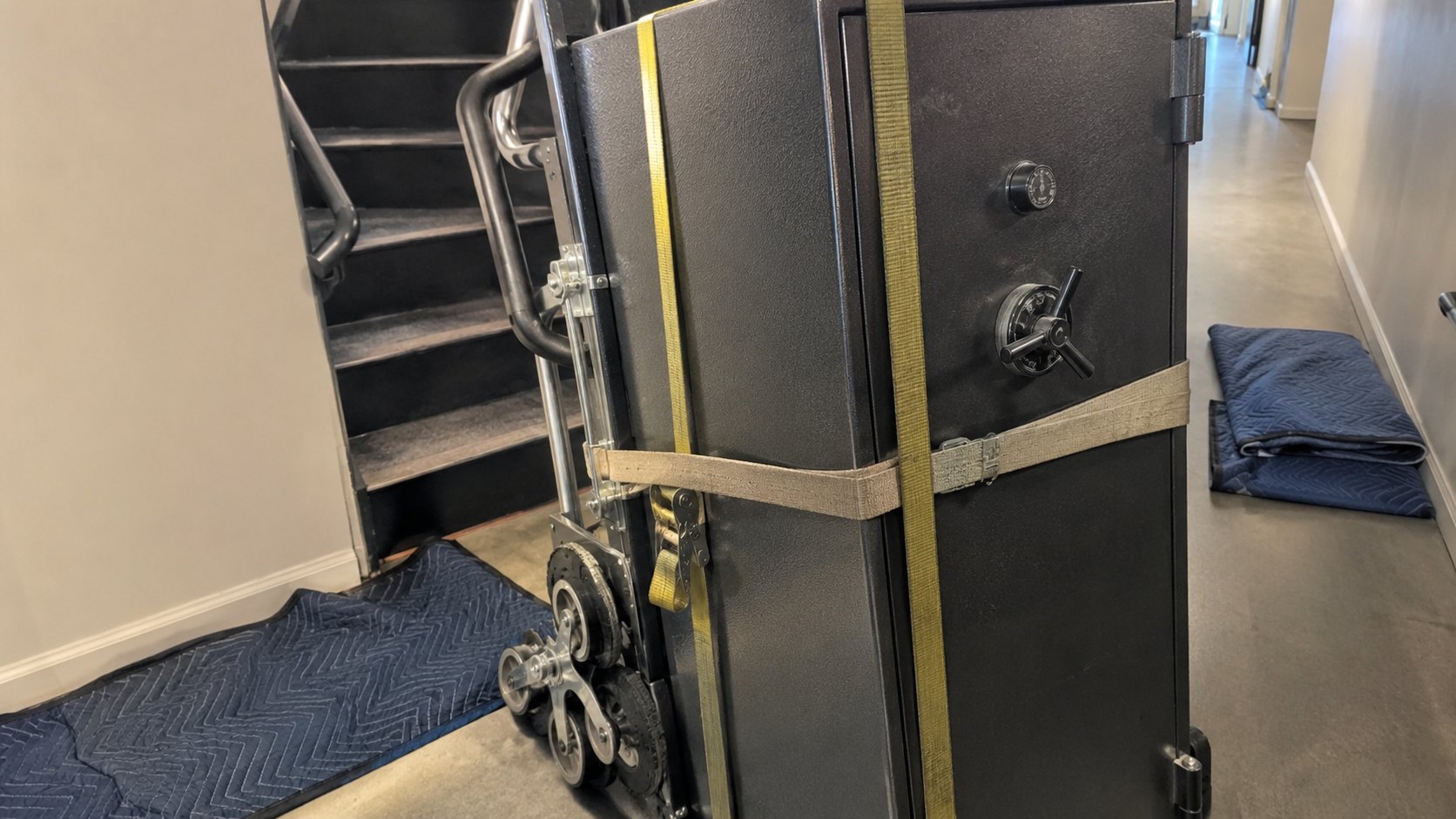 A gun safe strapped to a stair-climbing trolley with moving blankets and straps