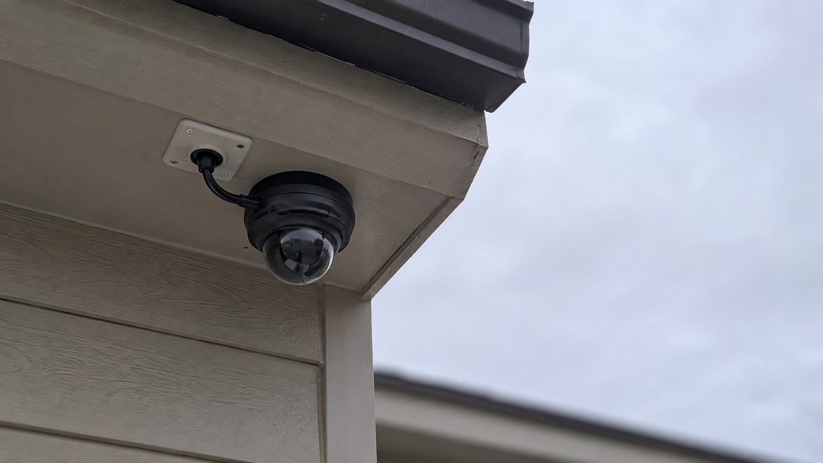 A small dome camera mounted under the eave of a house