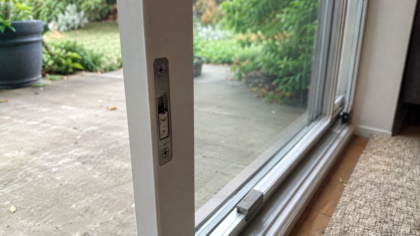 A sliding patio door latch with a security bar laid in the bottom track
