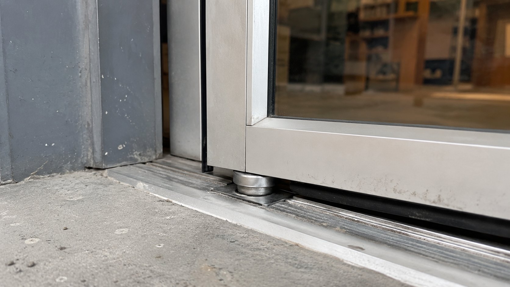 The bottom pivot and threshold of an aluminium storefront glass door